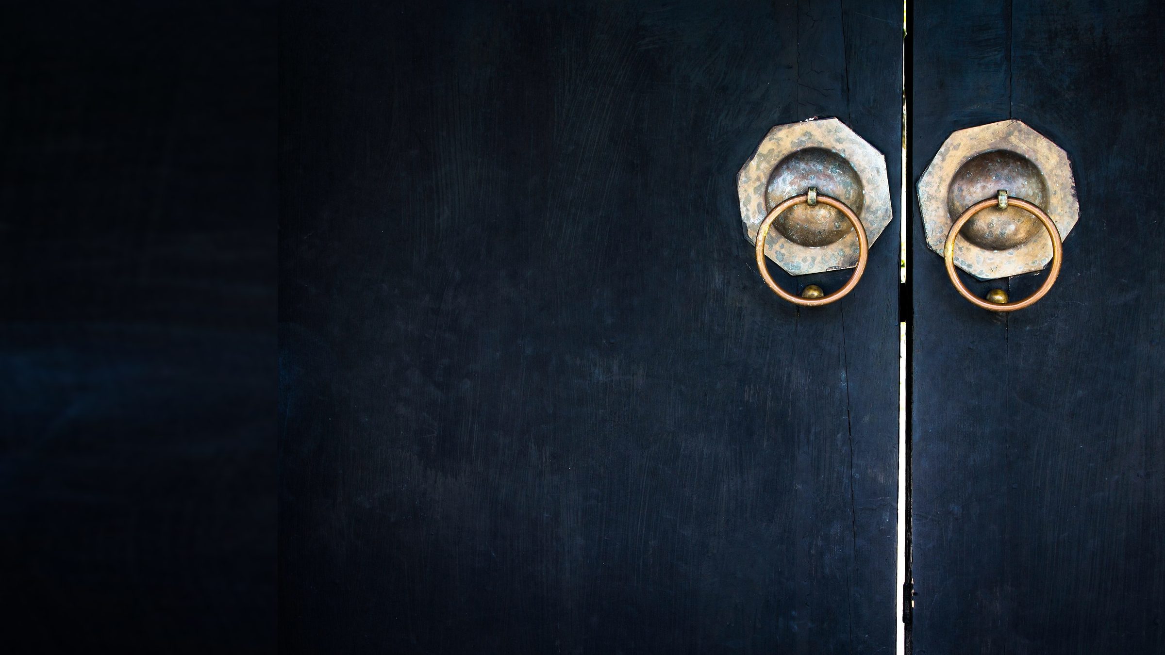 A dark double door with two brass ring knockers